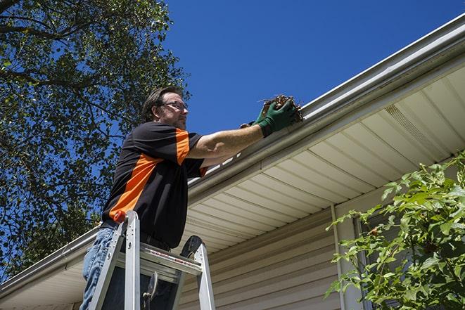 a specialist conducting gutter repair on a building in Ballston Lake, NY